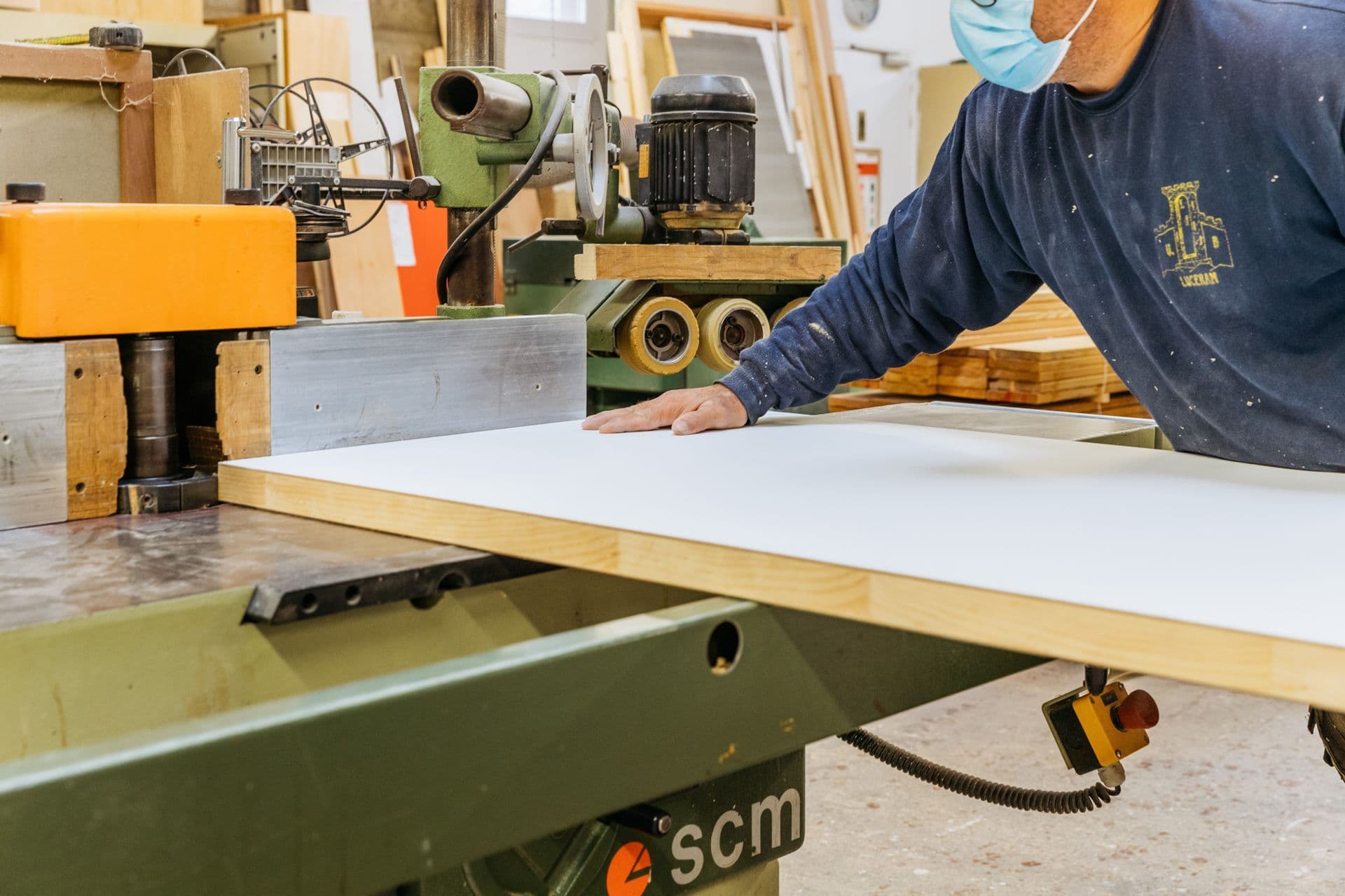 Un menuisier de l'atelier Sergent engage un panneau sur la toupie, dans l'atelier de Glisy.